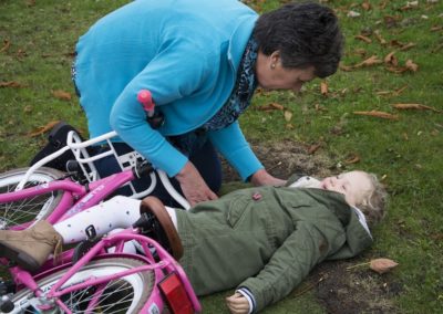 A young girl experiencing Body Stress Release while lying on the ground next to a bicycle.