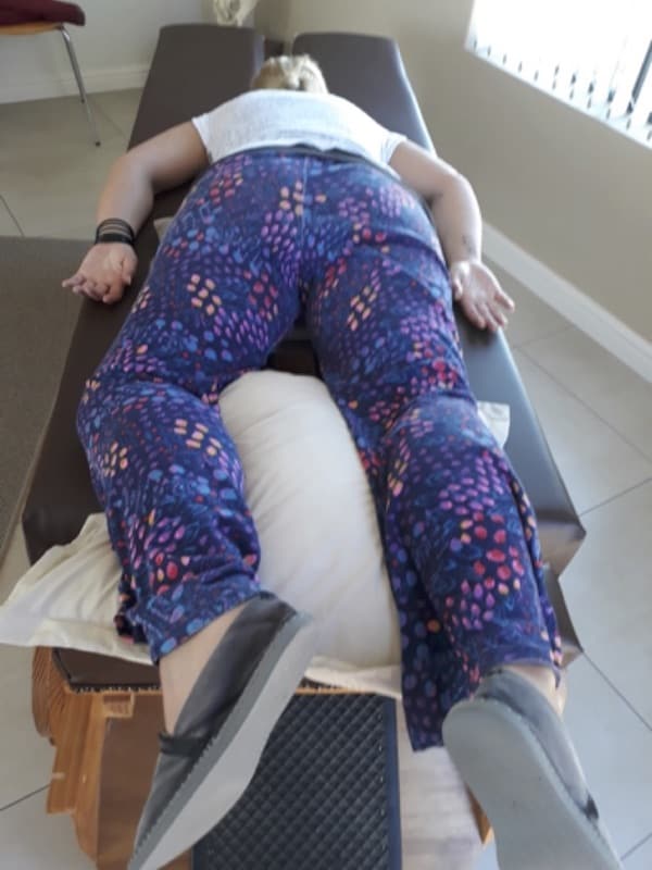 A woman laying on a massage table with a pillow experiencing Body Stress Release on her 2nd visit